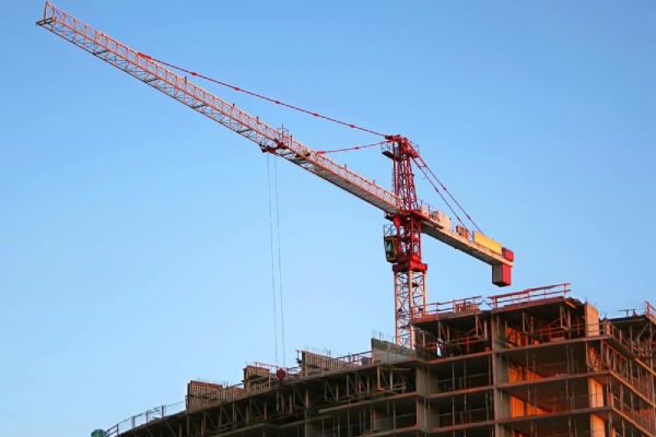 Hijskraan torent boven flatgebouw in aanbouw uit.