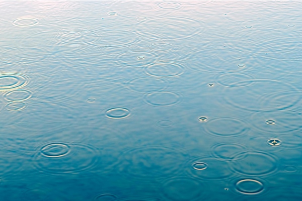 Regendruppels vallen in een wateroppervlak